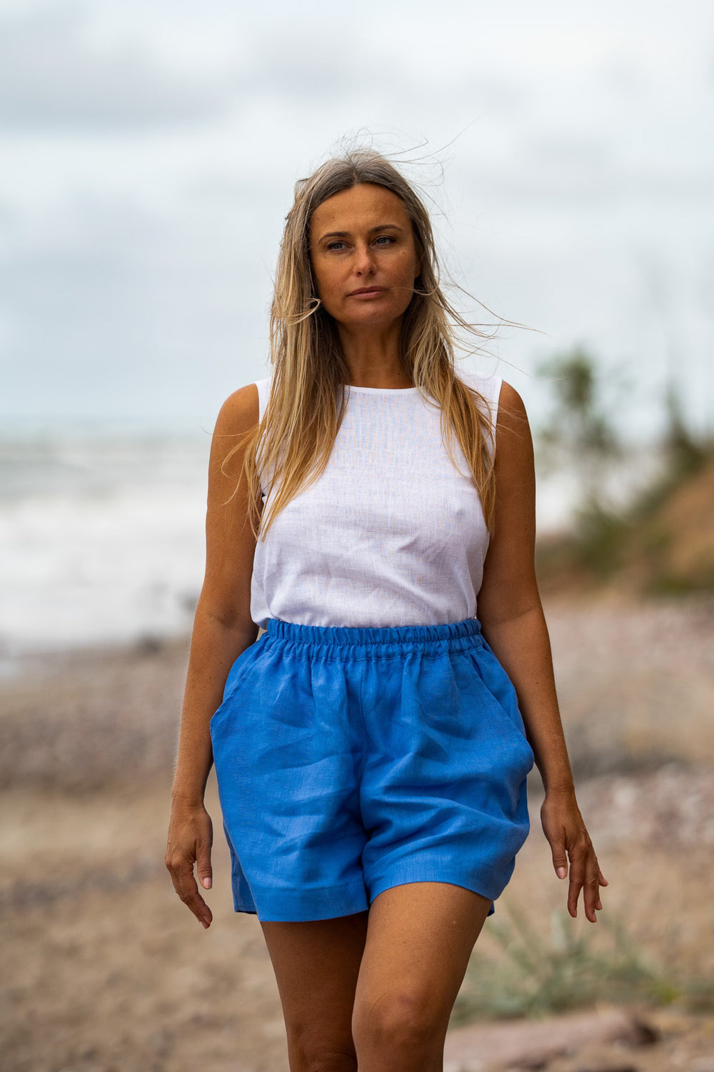 Model In Beach Demonstrates Linen Loose Shorts Ashley In Blue Color With White Linen Top - Daily Linen