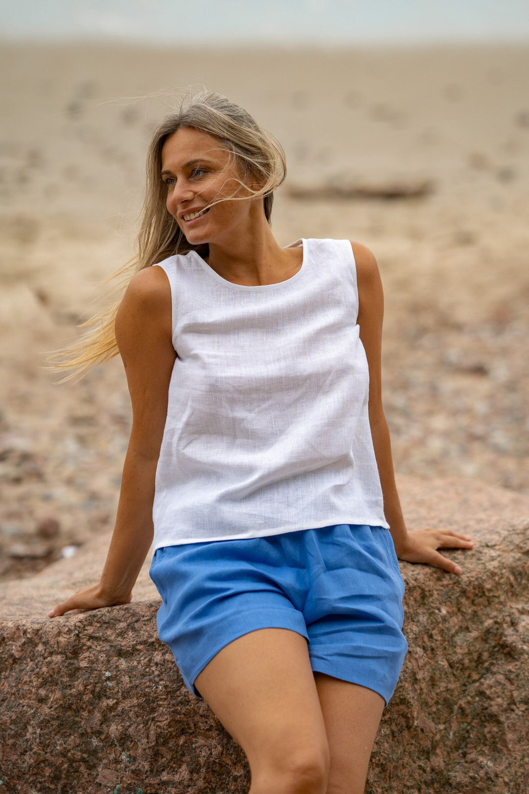 Model At Beach Demonstrates Linen Tank Top Teide In White Color With Blue Shorts - Daily Linen