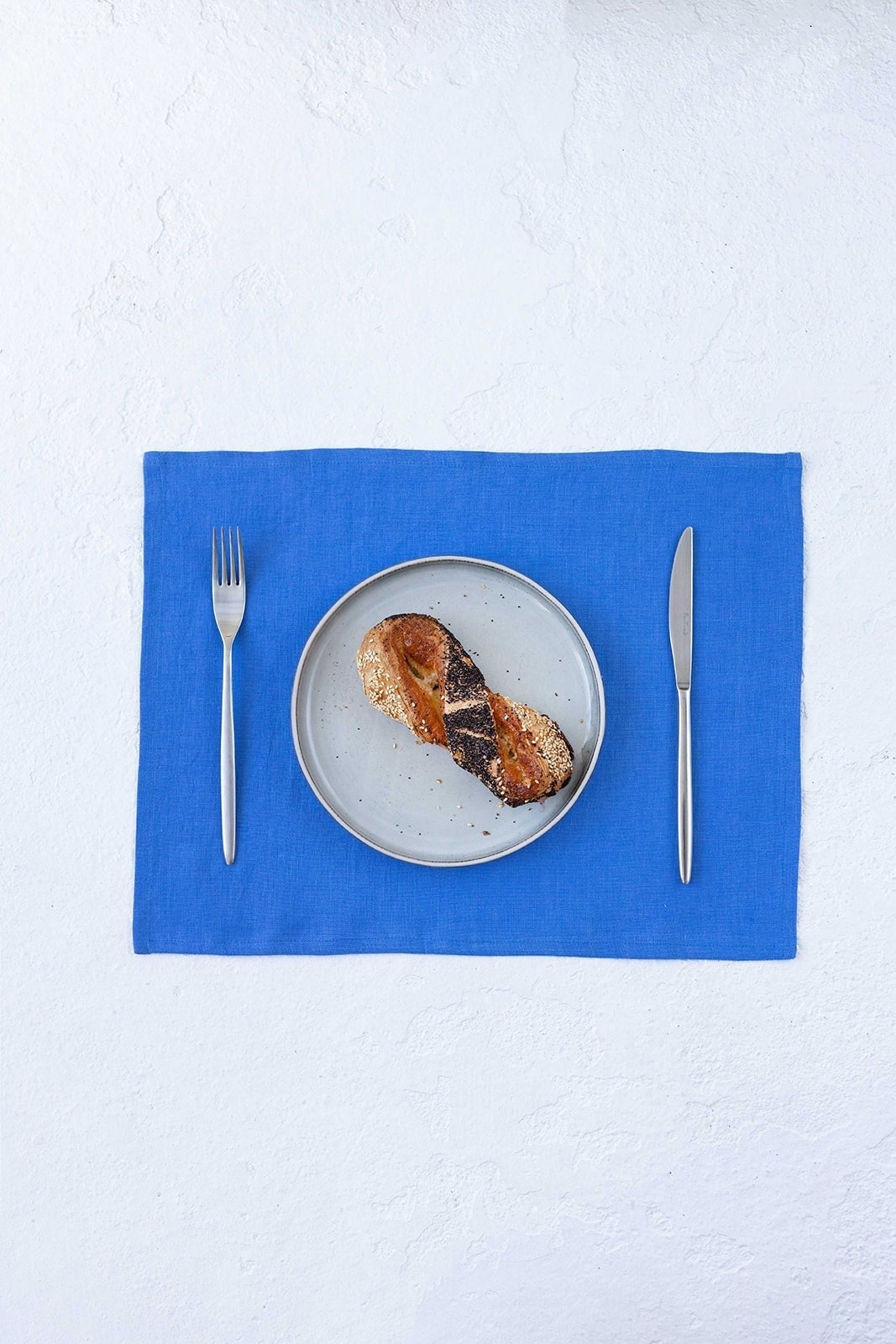 Blue linen placemat with plate and bun