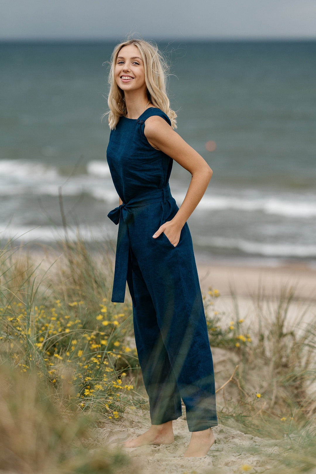 Model In Beach Demonstrates Linen Wrap Junpsuit Dicey In Midnight Blue Color - Daily Linen